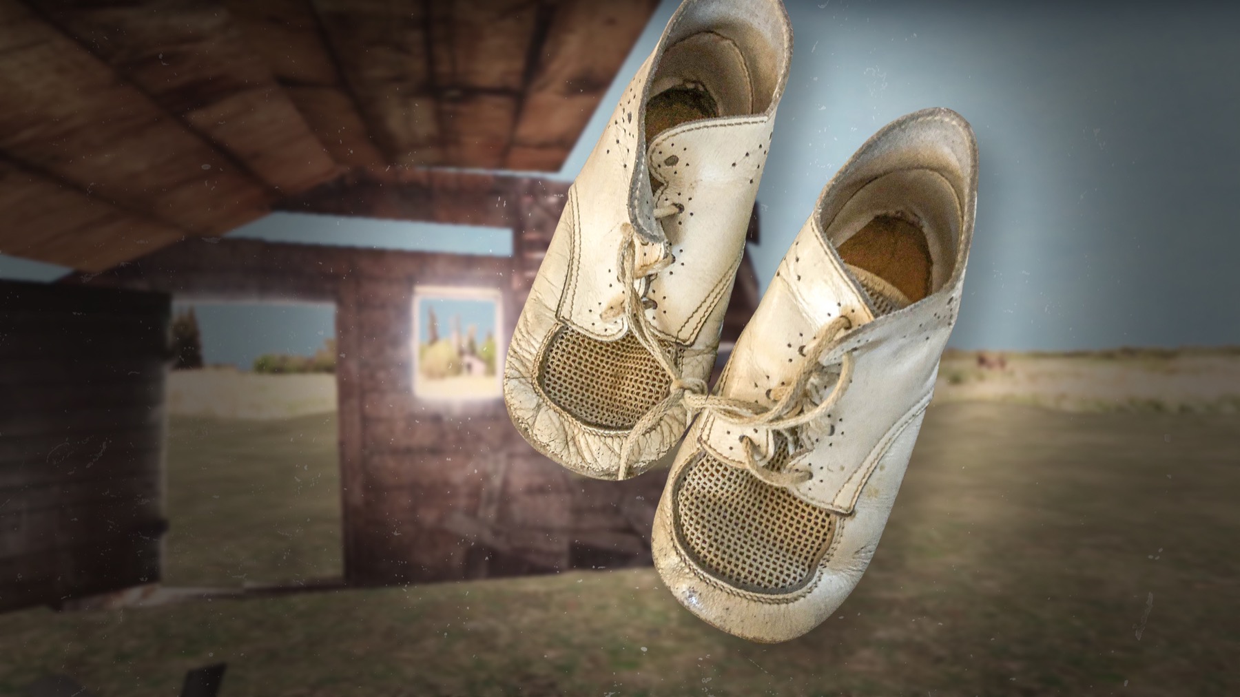 A pair of worn white baby shoes suspended in the air inside a barn