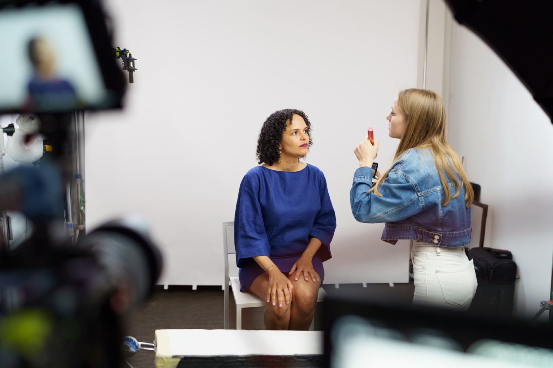 A laureate being prepared for her interview in a white studio, seen past the camera
