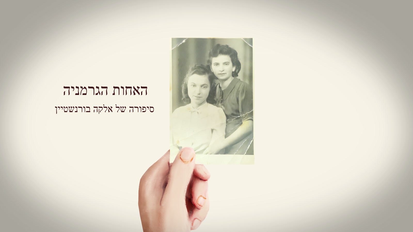 Film still: a hand holding the photograph of Elka and Hildegard, beside the film's Hebrew title