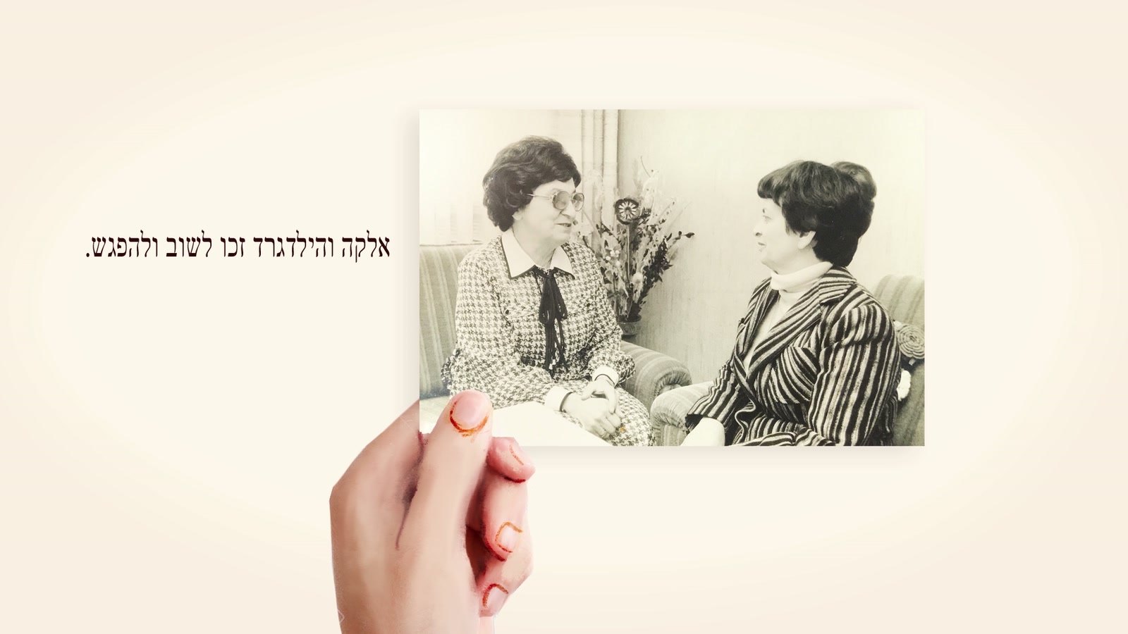 Film still: a hand holding the photograph of Elka and Hildegard's reunion